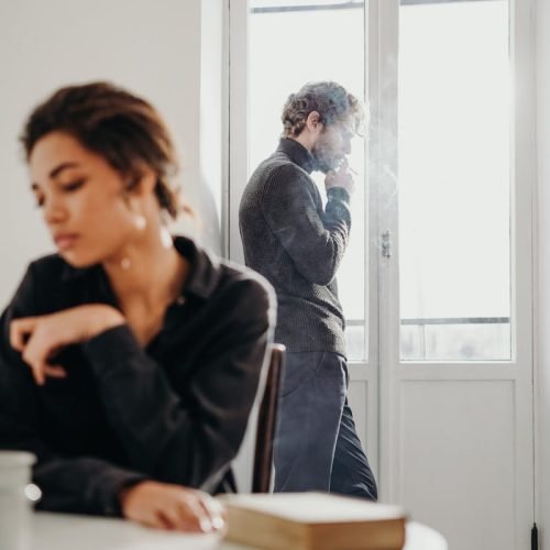 A couple experiencing tension and introspection indoors with a bright window.