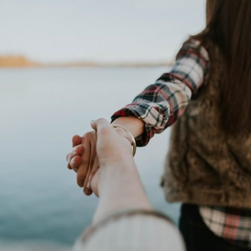shallow focus photography of man and woman holding hands